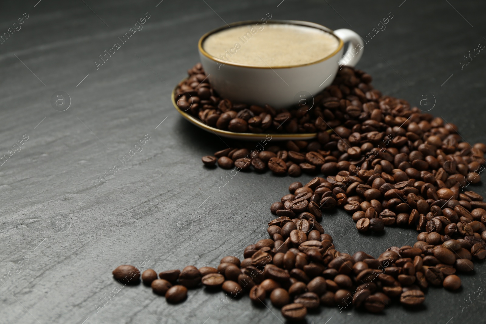 Aromatic coffee in cup and heart shaped of beans on black table, closeup. Space for text Photo of Aromatic coffee in cup and heart shaped of beans on black table, closeup. Space for text