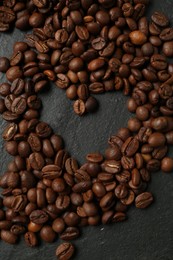 Photo of Heart shaped of coffee beans on black table, flat lay