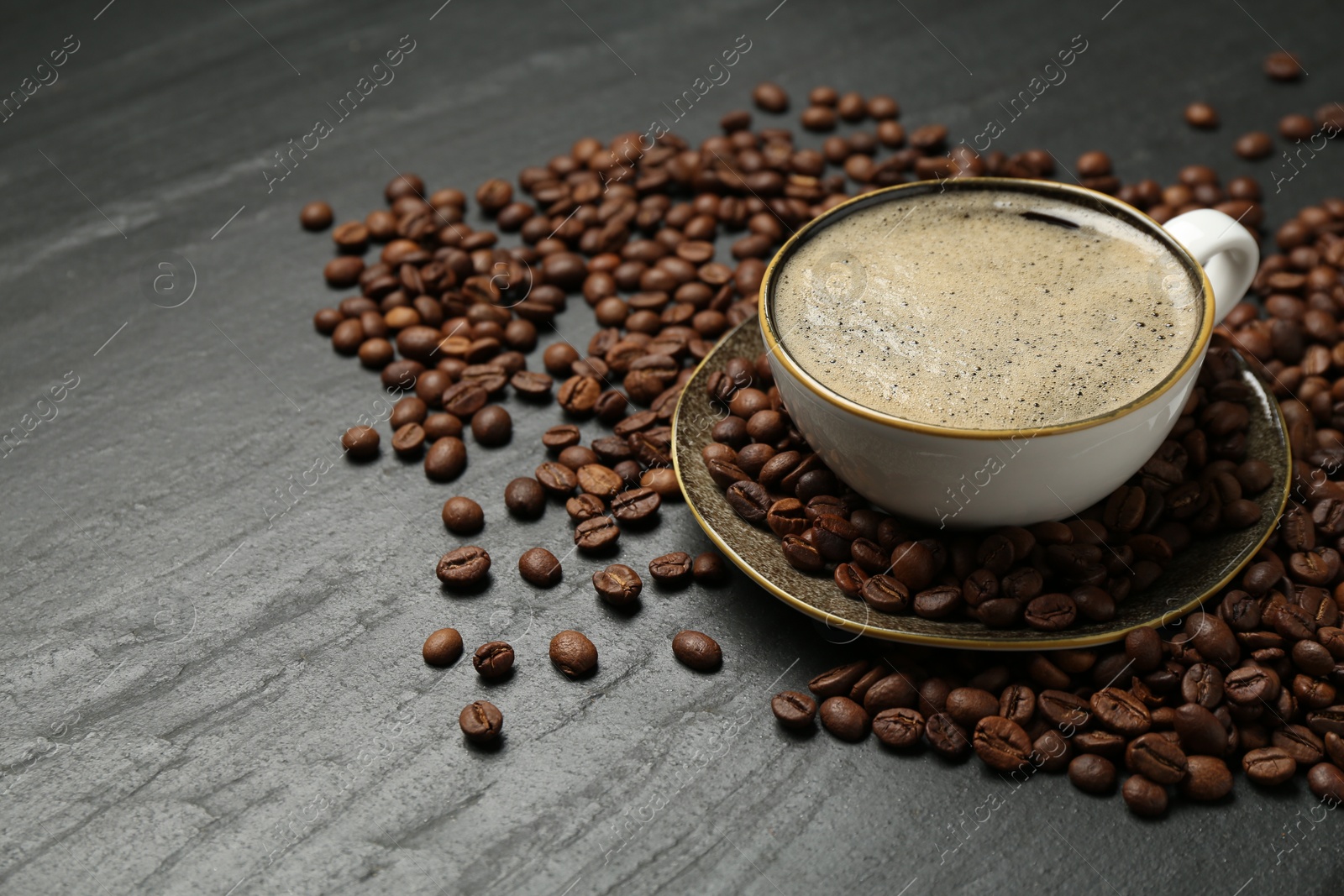 Aromatic coffee in cup and beans on black table, closeup. Space for text Photo of Aromatic coffee in cup and beans on black table, closeup. Space for text
