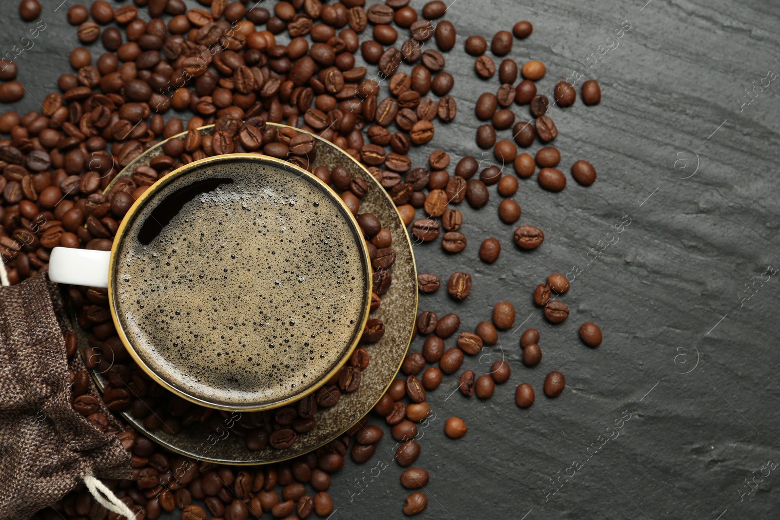 Aromatic coffee in cup and beans on black table, flat lay. Space for text Photo of Aromatic coffee in cup and beans on black table, flat lay. Space for text