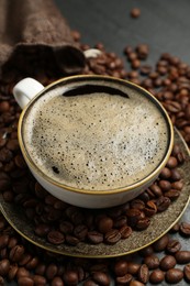 Photo of Aromatic coffee in cup and beans on table, closeup