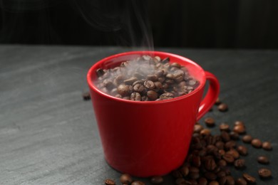 Photo of Aromatic coffee beans in cup on black table, closeup