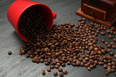 Photo of Aromatic coffee beans and grinder on black table, closeup
