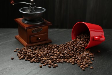 Photo of Aromatic coffee beans and grinder on black table