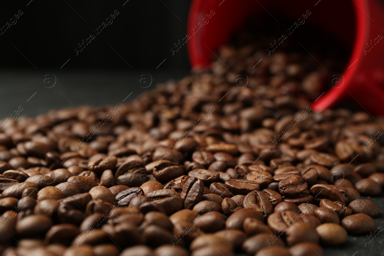 Aromatic coffee beans and overturned cup on table, closeup Photo of Aromatic coffee beans and overturned cup on table, closeup