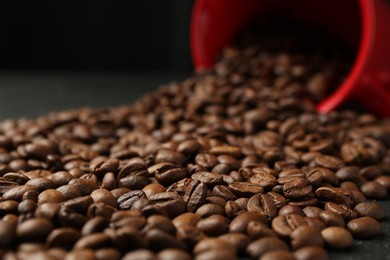 Photo of Aromatic coffee beans and overturned cup on table, closeup
