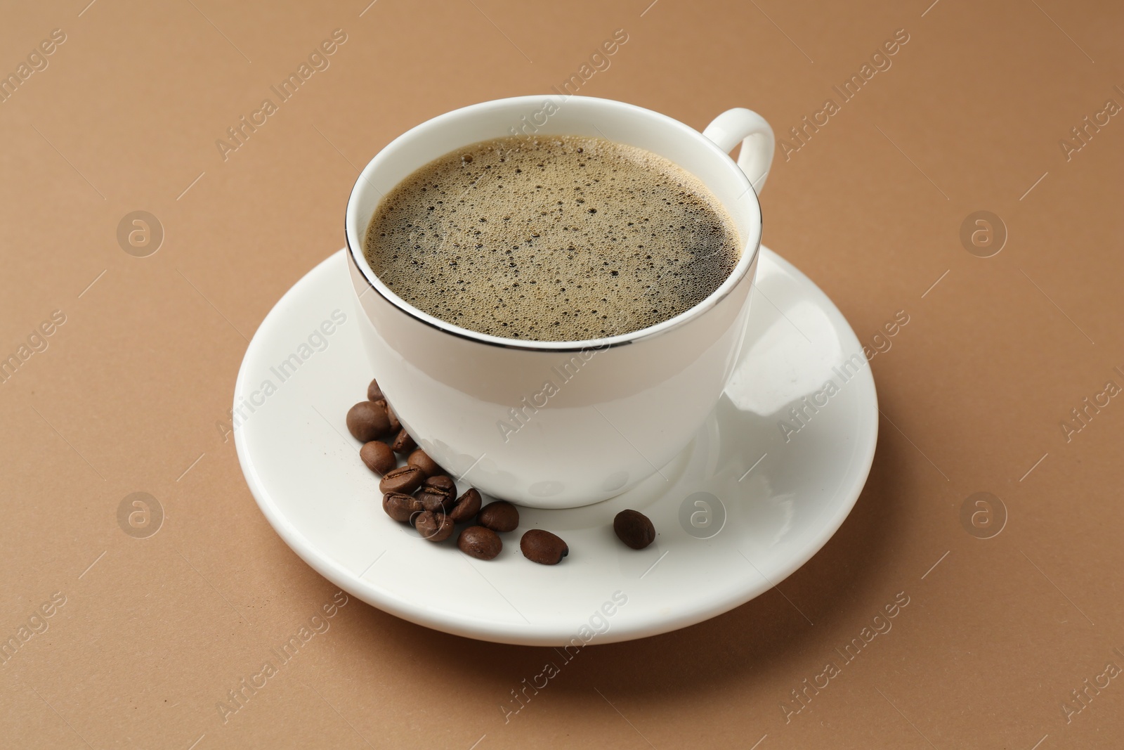Aromatic coffee in cup and beans on beige background, closeup Photo of Aromatic coffee in cup and beans on beige background, closeup