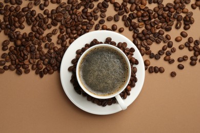Photo of Aromatic coffee in cup and beans on beige background, flat lay