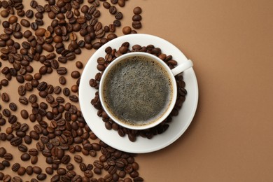 Photo of Aromatic coffee in cup and beans on beige background, flat lay