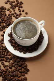 Photo of Aromatic coffee in cup and beans on beige background, above view