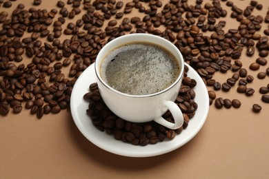 Photo of Aromatic coffee in cup and beans on beige background, above view