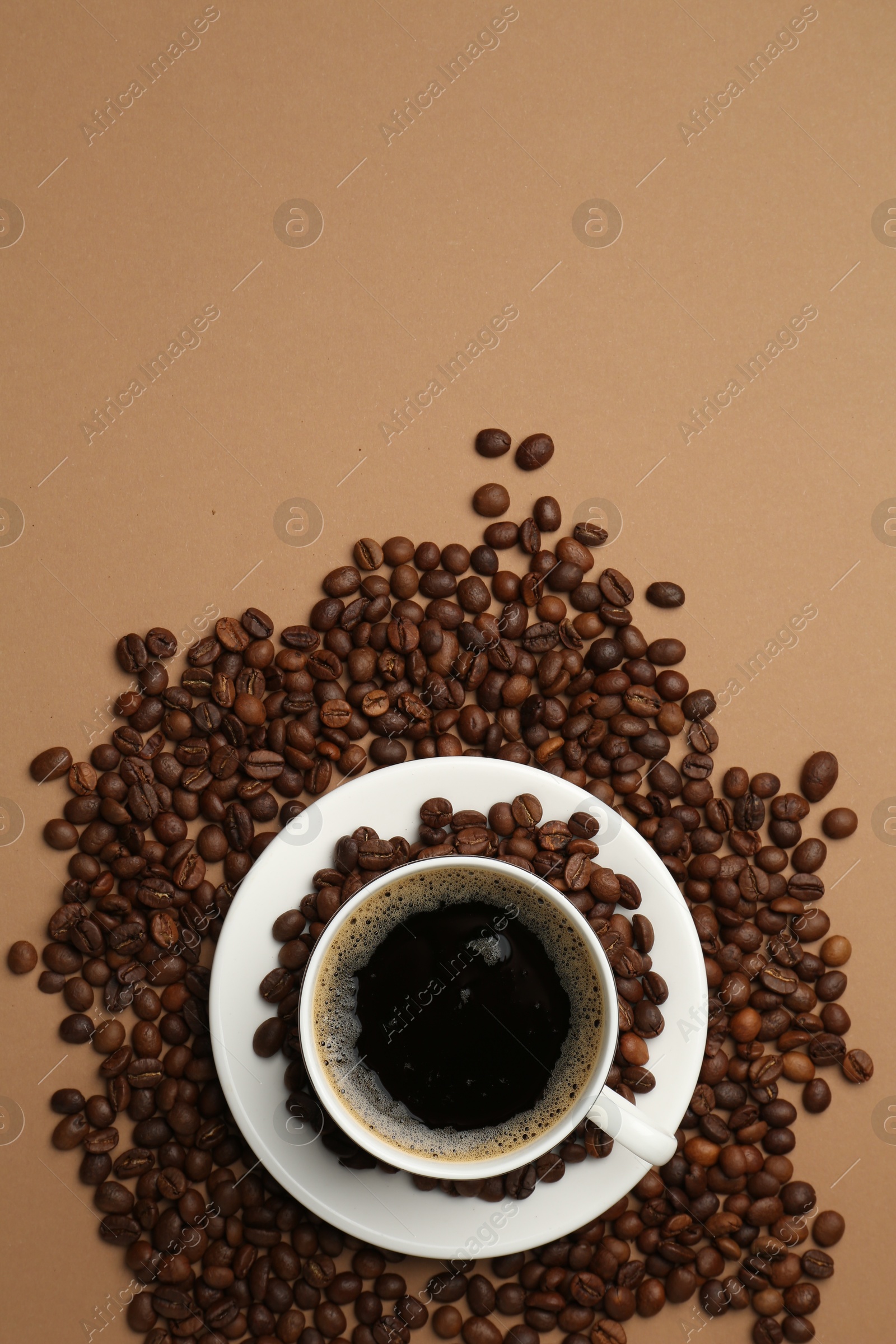 Aromatic coffee in cup and beans on beige background, flat lay. Space for text Photo of Aromatic coffee in cup and beans on beige background, flat lay. Space for text