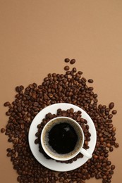 Photo of Aromatic coffee in cup and beans on beige background, flat lay. Space for text