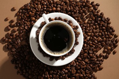 Photo of Aromatic coffee in cup and beans on beige background, flat lay