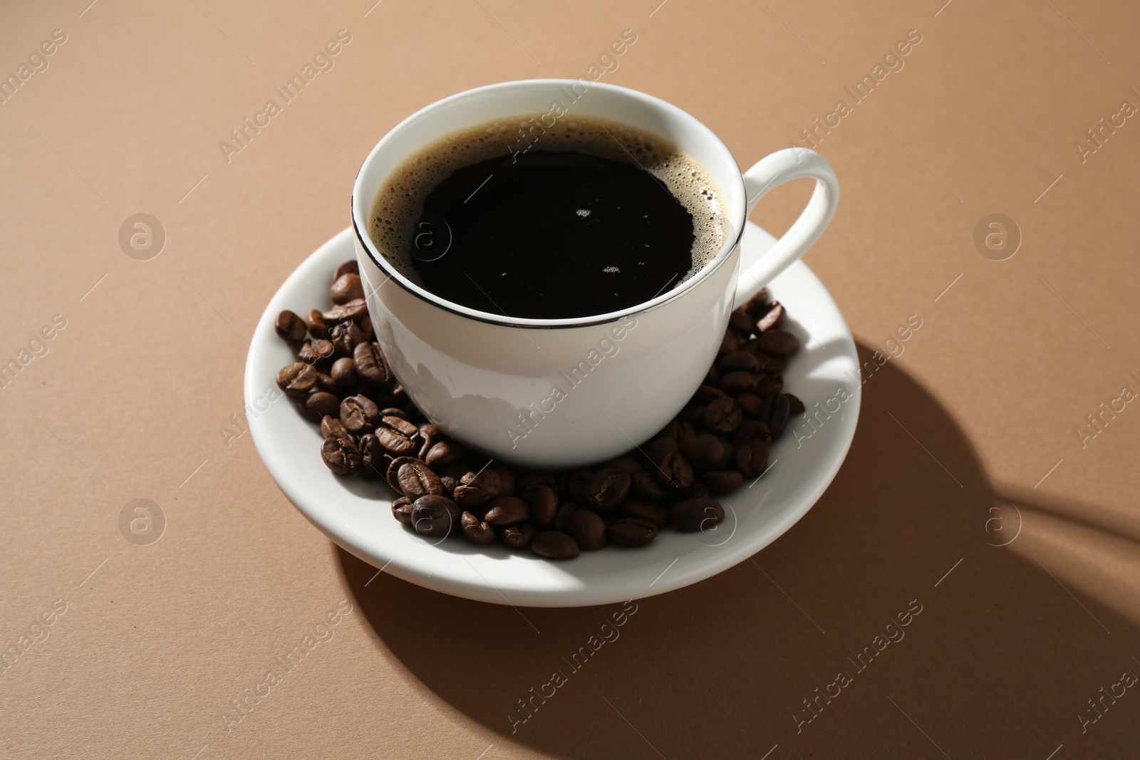 Aromatic coffee in cup and beans on beige background, closeup Photo of Aromatic coffee in cup and beans on beige background, closeup