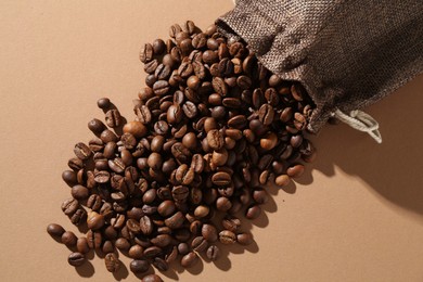 Photo of Aromatic coffee beans and sack on beige background, top view