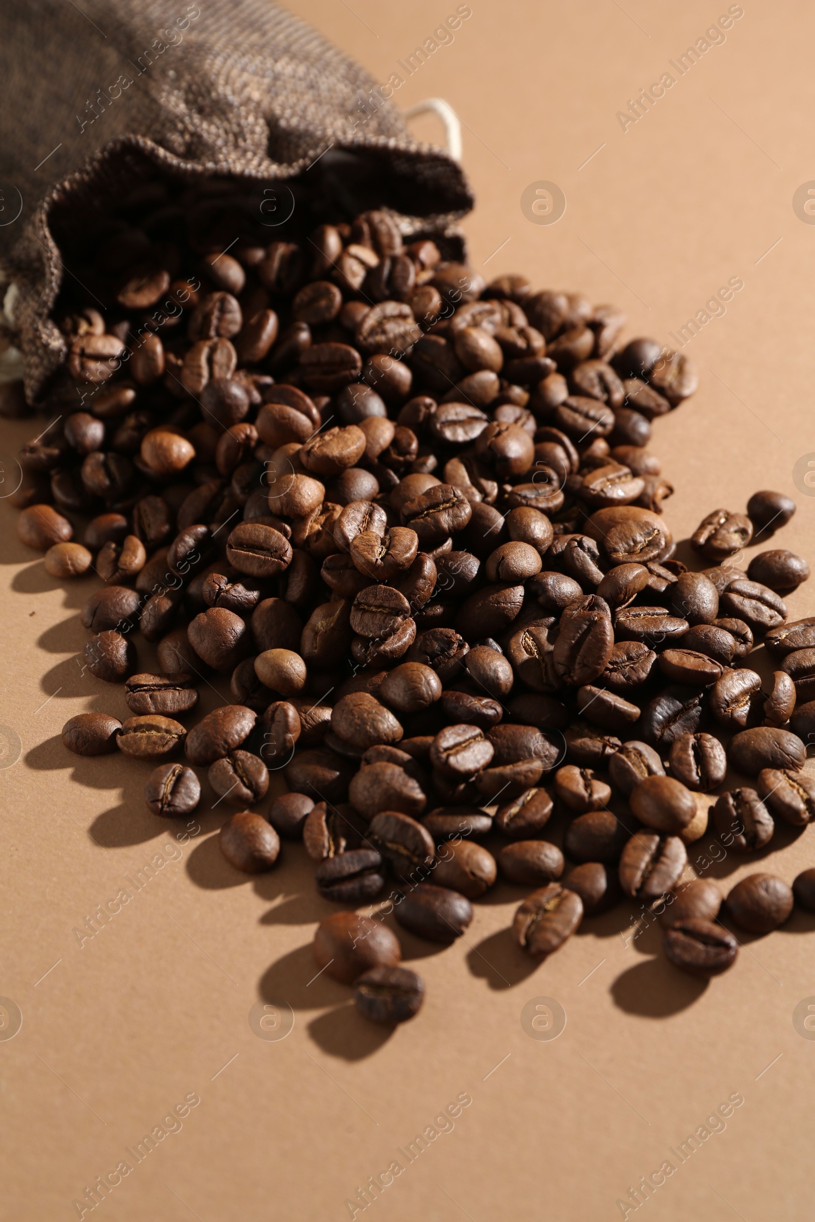 Aromatic coffee beans and sack on beige background, closeup Photo of Aromatic coffee beans and sack on beige background, closeup