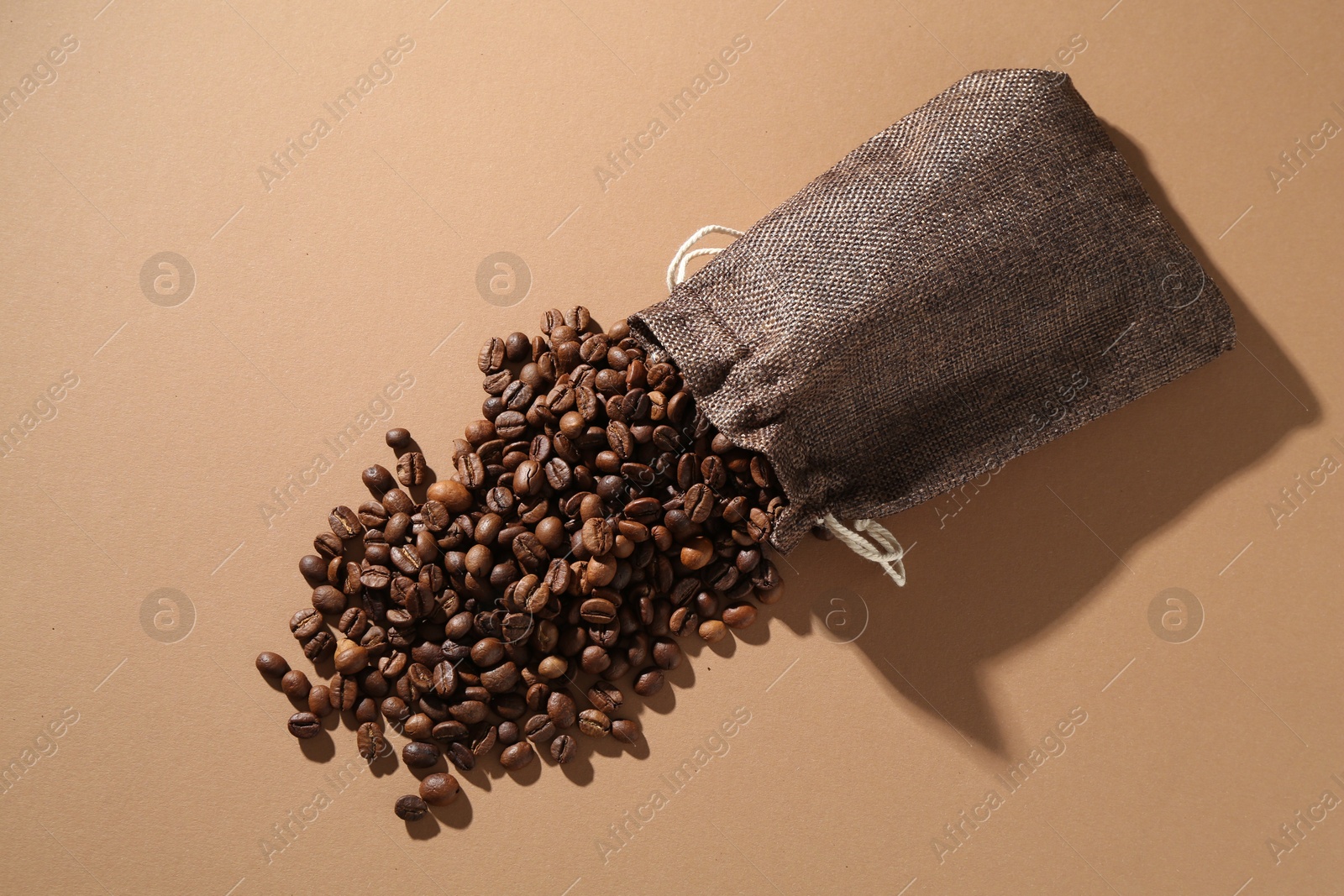 Aromatic coffee beans and sack on beige background, top view Photo of Aromatic coffee beans and sack on beige background, top view