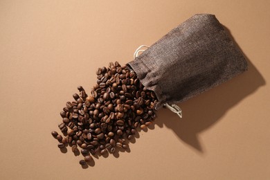 Photo of Aromatic coffee beans and sack on beige background, top view