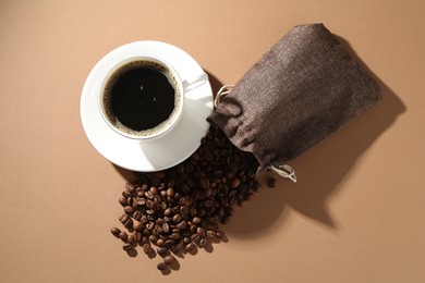 Photo of Aromatic coffee in cup and beans on beige background, flat lay