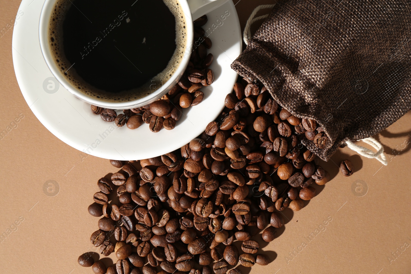Aromatic coffee in cup and beans on beige background, flat lay Photo of Aromatic coffee in cup and beans on beige background, flat lay