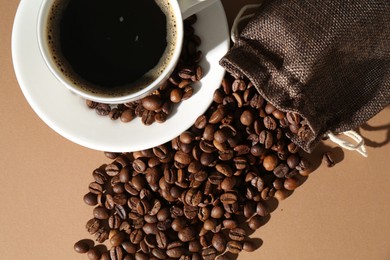 Photo of Aromatic coffee in cup and beans on beige background, flat lay
