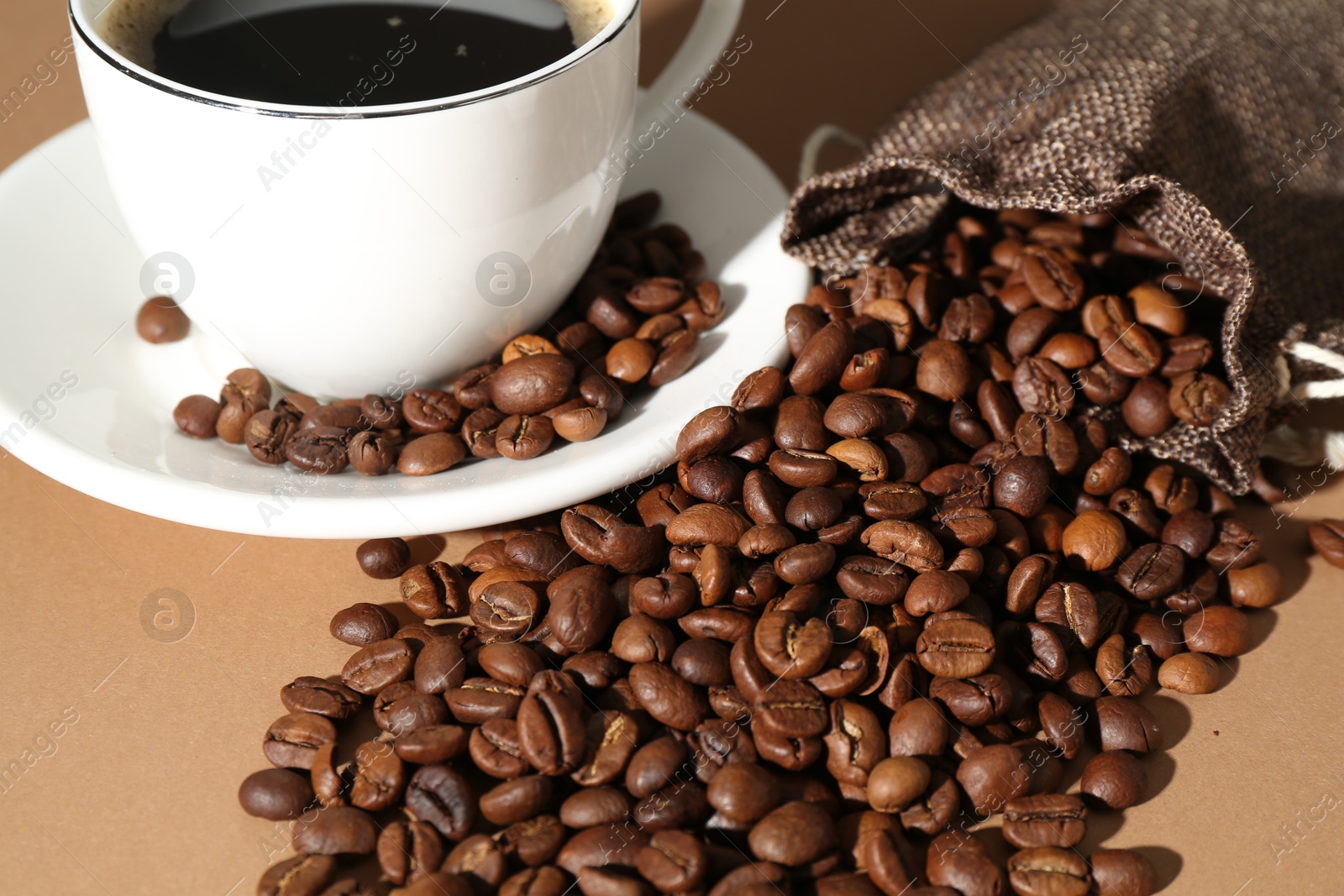 Aromatic coffee in cup and beans on beige background, closeup Photo of Aromatic coffee in cup and beans on beige background, closeup