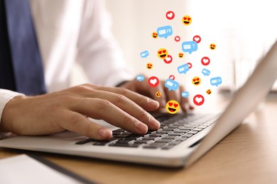 Image of Man using laptop at table, closeup. Social media notifications (messages, likes, emojis) flying out of computer