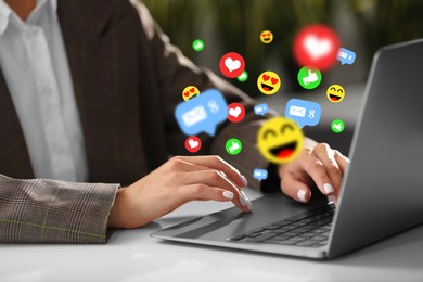 Image of Woman using laptop at table, closeup. Social media notifications (likes, messages and emojis) flying out of computer