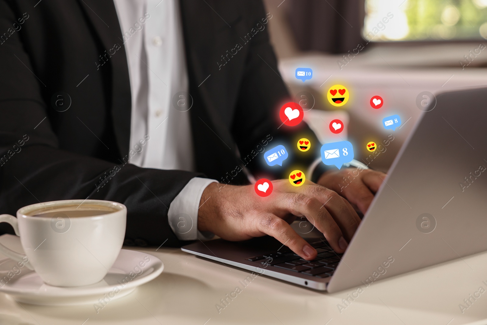 Man using laptop at table, closeup. Social media notifications (likes, messages and emojis) flying out of computer Image of Man using laptop at table, closeup. Social media notifications (likes, messages and emojis) flying out of computer