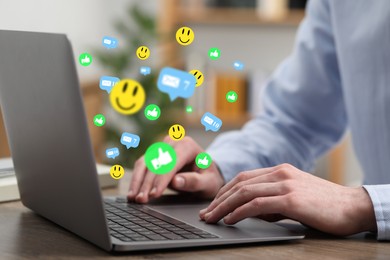 Image of Man using laptop at table, closeup. Social media notifications (likes, messages and emojis) flying out of computer