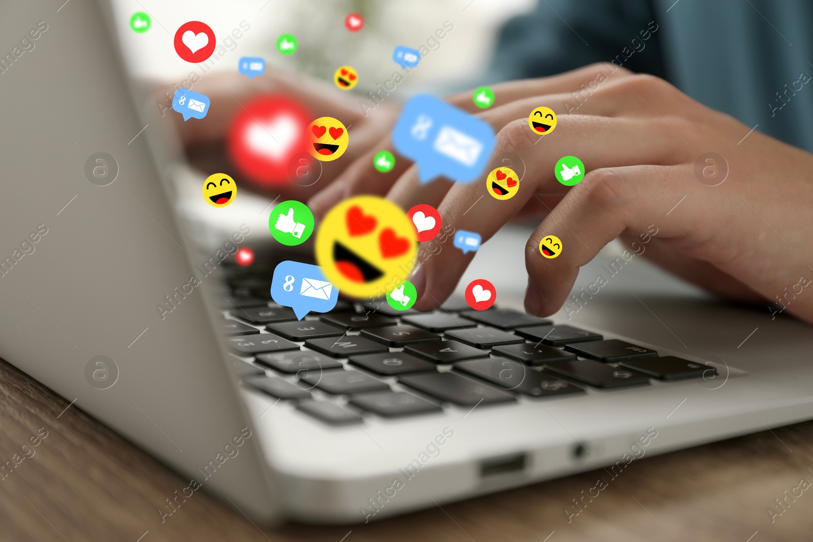 Woman using laptop at table, closeup. Social media notifications (likes, messages and emojis) flying out of computer Image of Woman using laptop at table, closeup. Social media notifications (likes, messages and emojis) flying out of computer