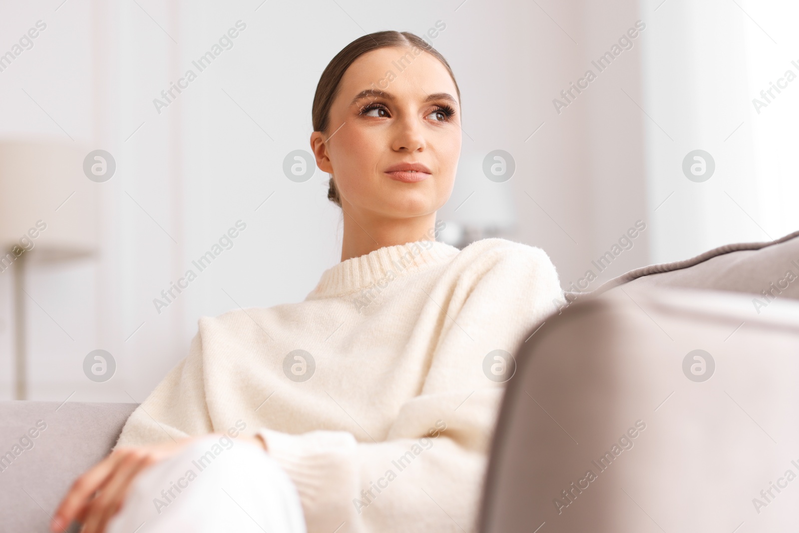 Portrait of beautiful young woman on sofa at home Photo of Portrait of beautiful young woman on sofa at home