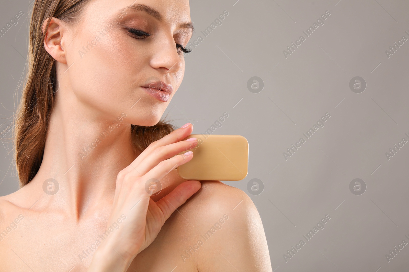 Beautiful woman with soap bar on grey background, closeup. Space for text Photo of Beautiful woman with soap bar on grey background, closeup. Space for text