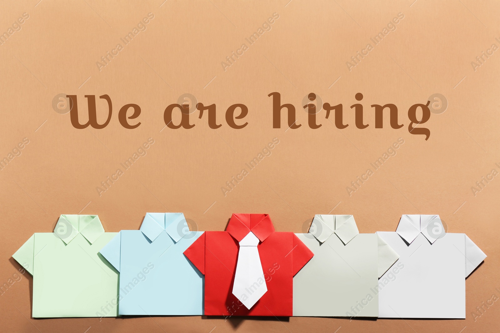 We Are Hiring. Many paper shirts on brown background, flat lay. Recruitment, human resource concept Image of We Are Hiring. Many paper shirts on brown background, flat lay. Recruitment, human resource concept