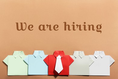 Image of We Are Hiring. Many paper shirts on brown background, flat lay. Recruitment, human resource concept