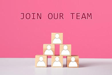 Image of Join Our Team. Pyramid of wooden cubes with human icons on white table against pink background. Recruitment, human resource concept
