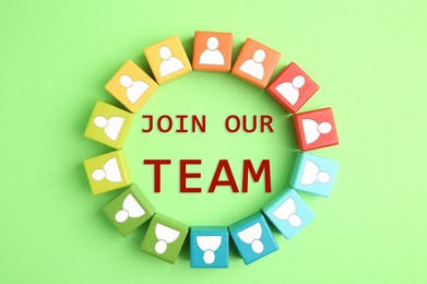 Image of Join Our Team. Circle of colorful cubes with human icons on light green background, top view. Recruitment, human resource concept