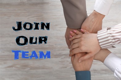 Image of Join Our Team. Group of people joining hands at light wooden table, top view. Recruitment, human resource concept