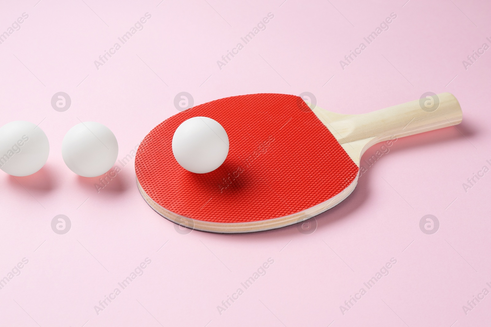 Ping pong racket and balls on pink background Photo of Ping pong racket and balls on pink background