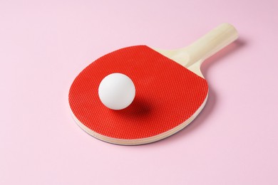 Photo of Ping pong racket and ball on pink background, closeup