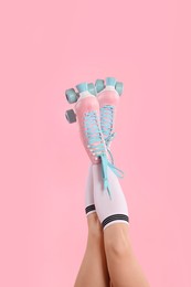 Photo of Woman in roller skates on pink background, closeup