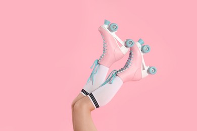 Photo of Woman in roller skates on pink background, closeup