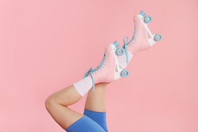 Photo of Woman in roller skates on pink background, closeup