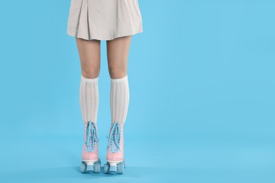 Photo of Woman in roller skates on light blue background, closeup. Space for text