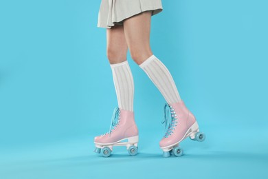 Photo of Woman in roller skates on light blue background, closeup
