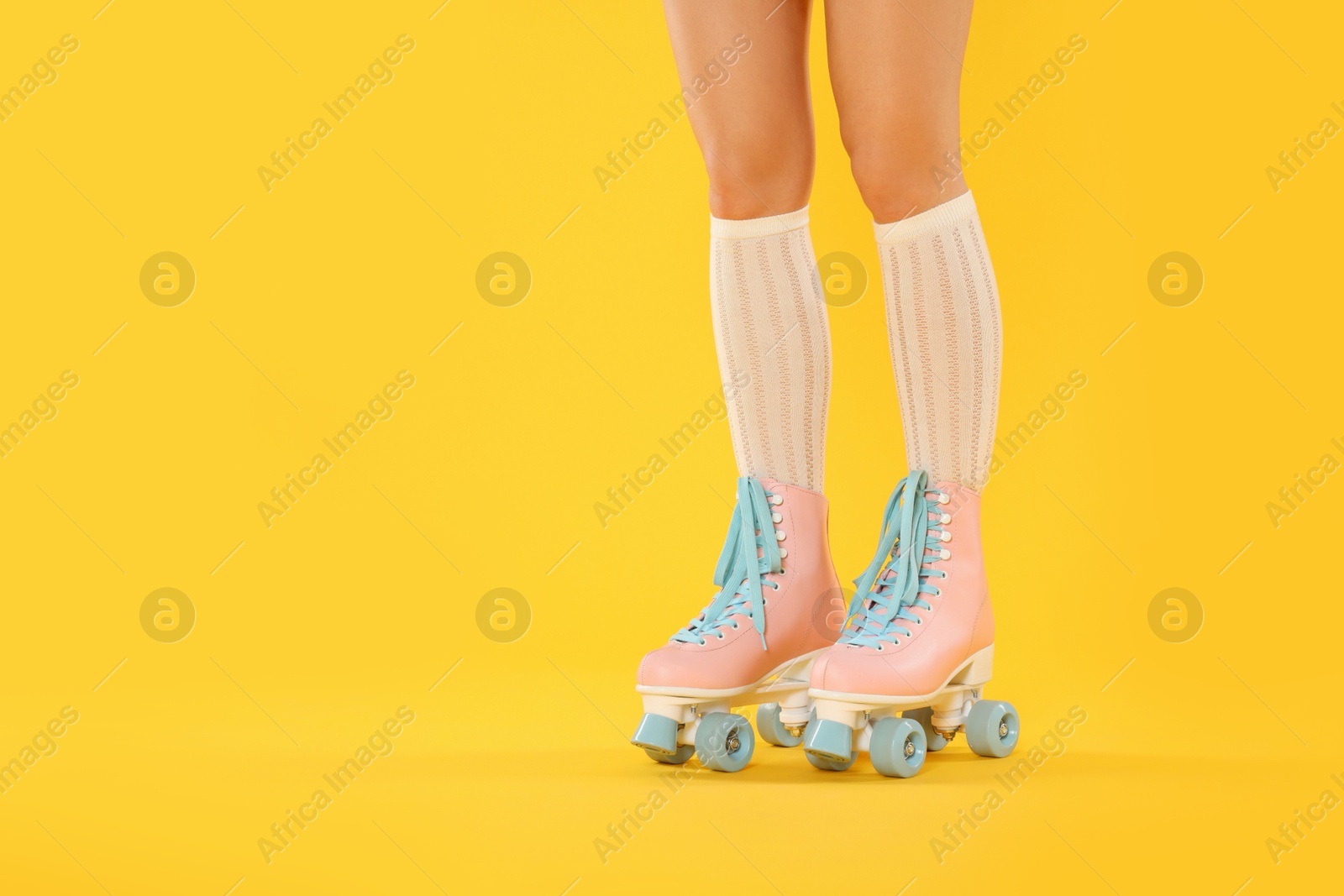 Woman in roller skates on orange background, closeup. Space for text Photo of Woman in roller skates on orange background, closeup. Space for text