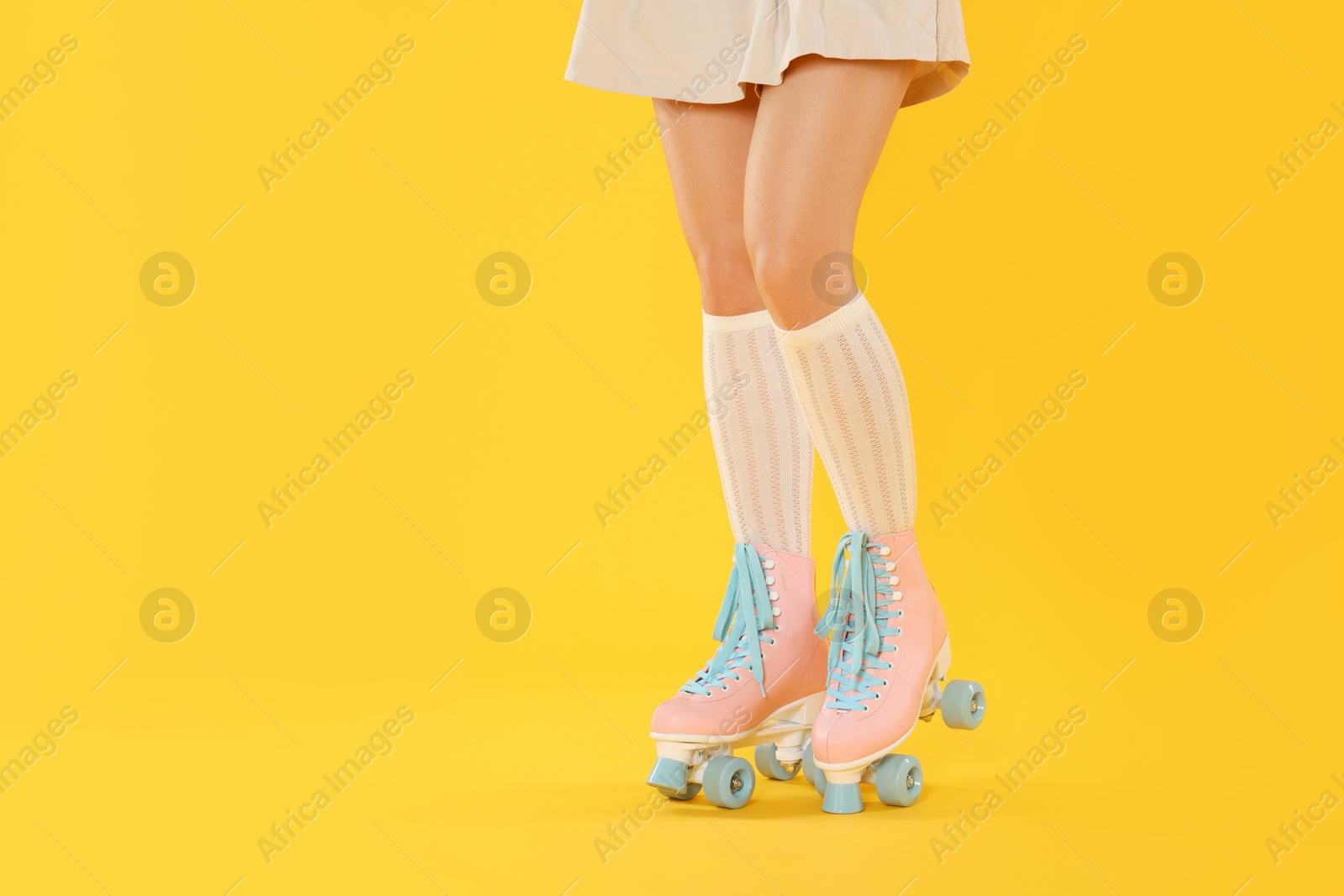Woman in roller skates on orange background, closeup. Space for text Photo of Woman in roller skates on orange background, closeup. Space for text