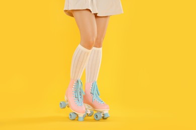 Photo of Woman in roller skates on orange background, closeup