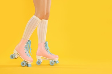 Photo of Woman in roller skates on orange background, closeup. Space for text